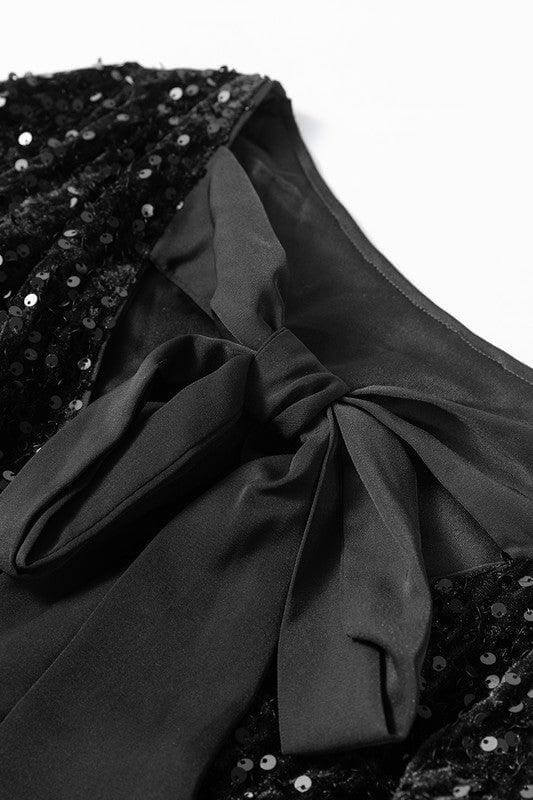 Black sequined dress with a large bow detail on a white background