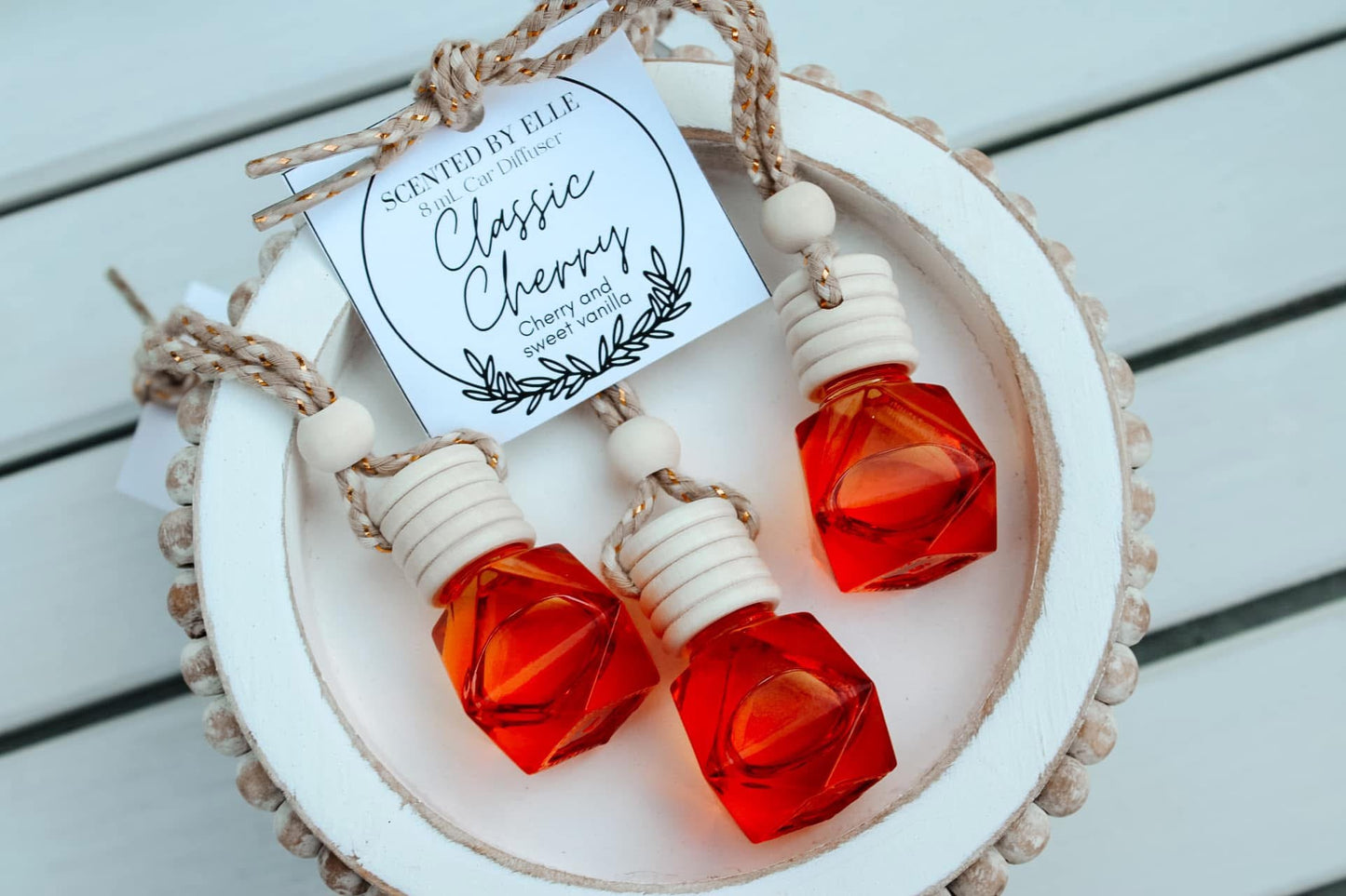 Two red perfume bottles with a decorative label on a wooden surface