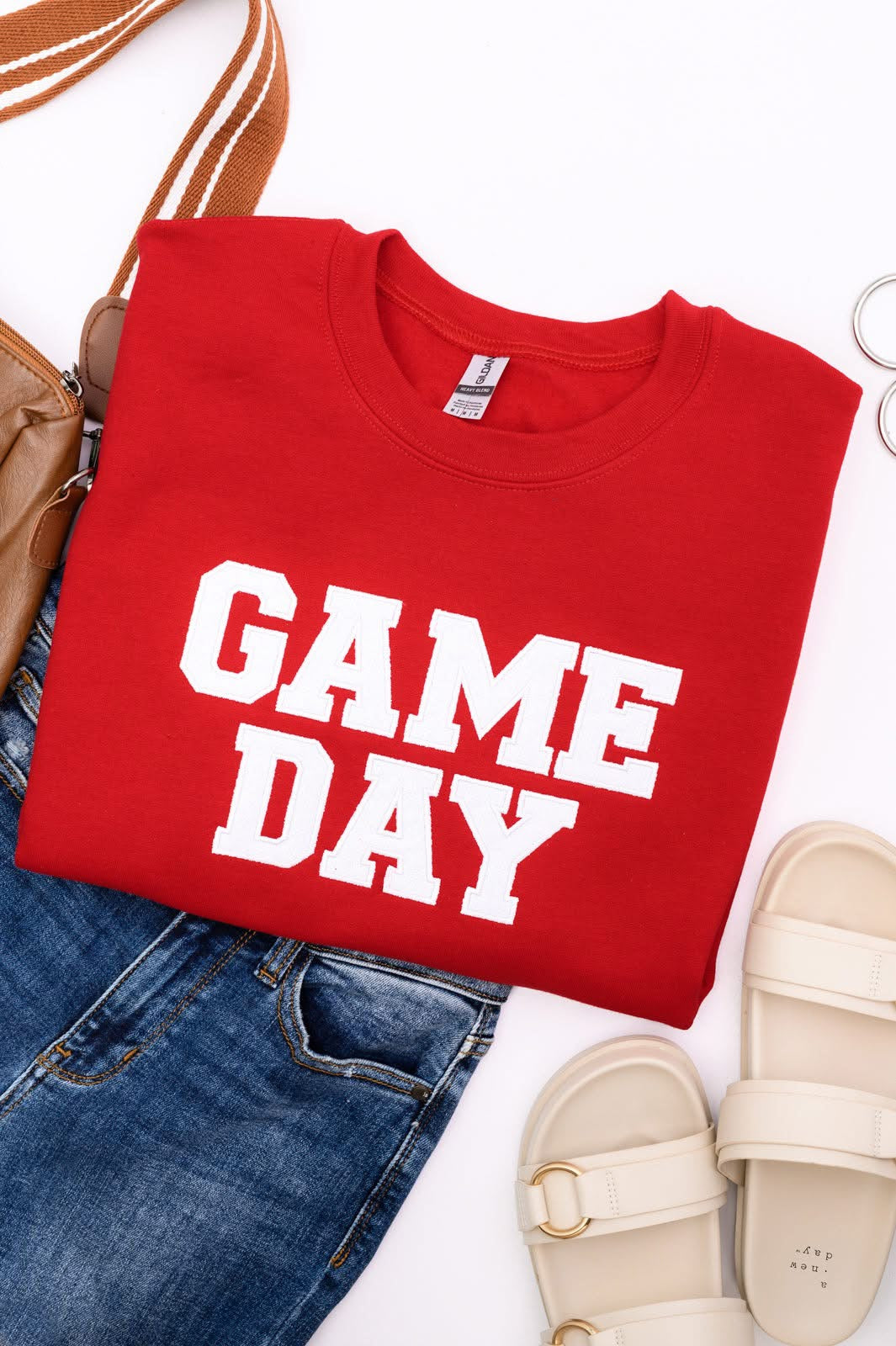 Red sweatshirt with 'GAME DAY' text, paired with jeans and sandals on a white background