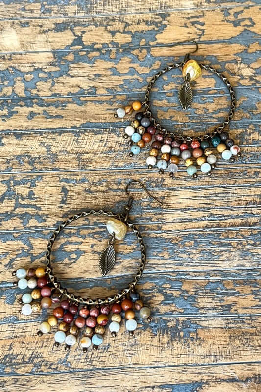 Fishhook earrings with large hoop. Features dangling small beads, with one larger bead in middle of hoop with small dangling feather.