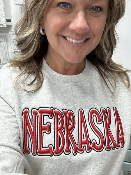 Person wearing a gray sweatshirt with 'NEBRASKA' printed in red.