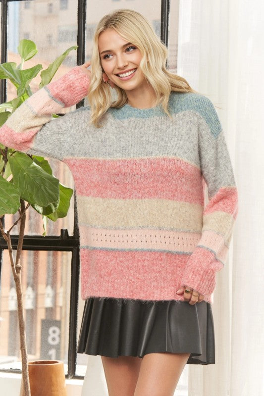 Woman wearing a colorful striped sweater and black skirt indoors.