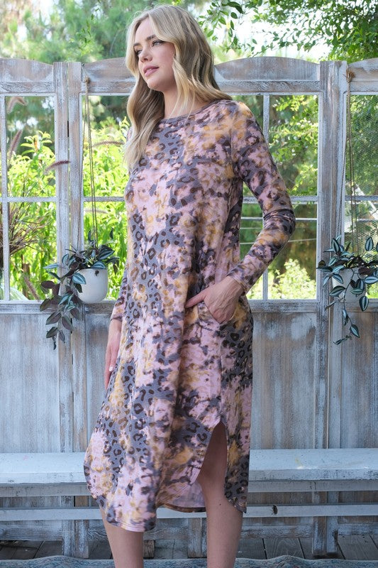 Woman wearing a leopard dress standing outdoors with a wooden fence and plants in the background