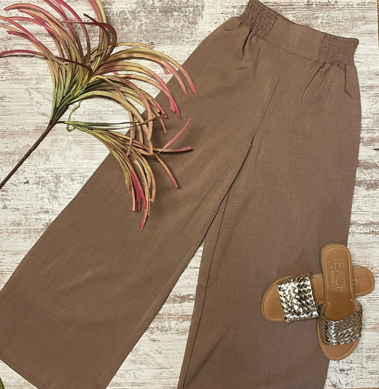 Brown pants with a decorative sandal on a wooden surface