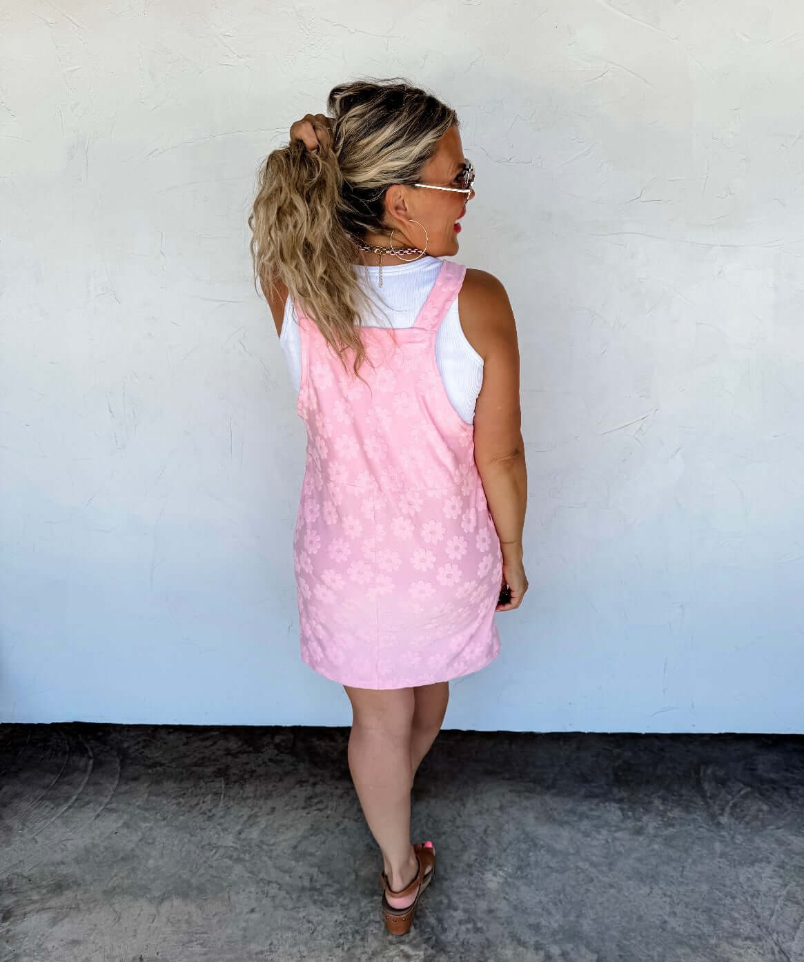 Woman wearing a pink dress with a white wall background