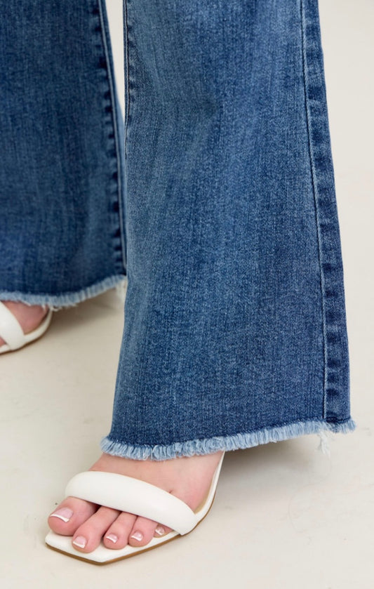 Close-up of blue jeans with a white sandal on a light background