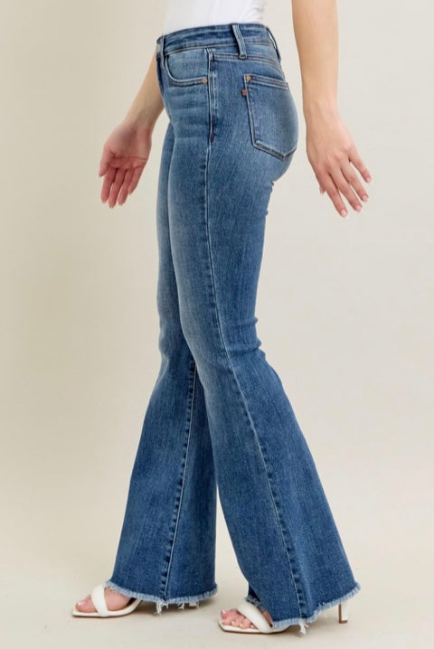 Person wearing blue flared jeans on a plain background