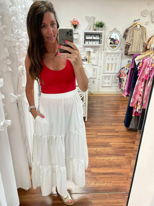 Woman wearing a red top and white skirt in a clothing store.