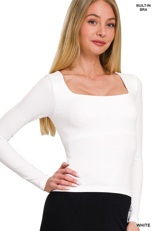 Woman wearing a white long-sleeve top with a square neckline on a plain background