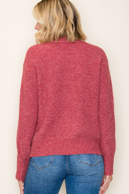 Person wearing a red sweater and blue jeans against a plain background