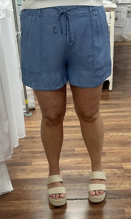 Person wearing blue shorts standing on a wooden floor.