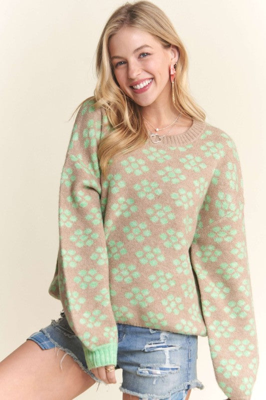 Woman wearing a pink sweater with green leaf pattern against a beige background