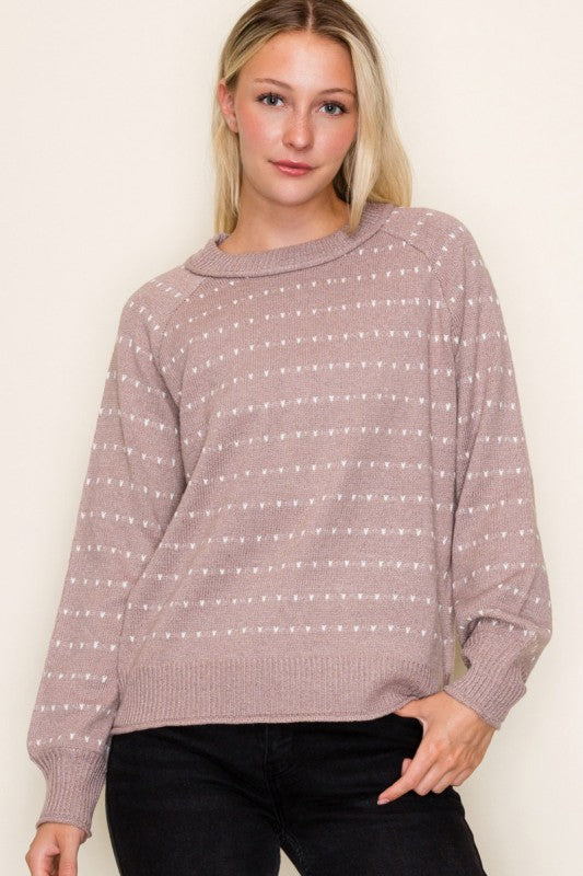 Woman wearing a mauve sweater with white stripes against a plain background